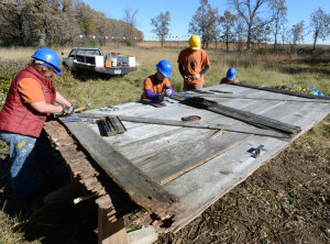 Four HPC corps members working on repairing barn door in field